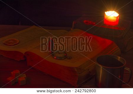 Old Book On The Table. The Open Holy Bible Is On The Table. Vintage Pocket Watch. A Burning Candle O