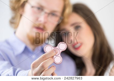 Millennials Couple Being Amazed By Simple Toy. Man And Woman Playing With Pink Fidget Spinner, Tryin