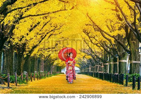 Beautiful Girl Wearing Japanese Traditional Kimono At Row Of Yellow Ginkgo Tree In Autumn. Autumn Pa