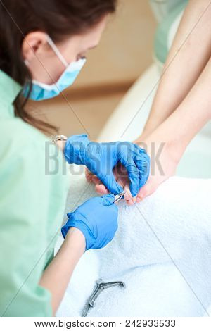 Woman Receiving Cuticle In Manicure Pedicure Salon. Patient On Medical Pedicure Procedure, Visiting 