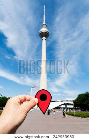 closeup of the hand of a young caucasian man with a red marker at the Berliner Fernsehturm, the popular television tower of Berlin, in Germany