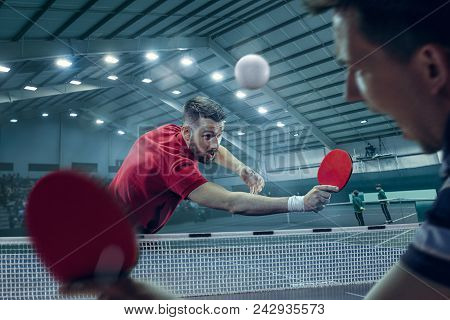 The Table Tennis Player In Motion. Fit Young Sports Man Tennis-player In Play On Sport Arena Backgro