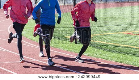 Four Track And Field Athletes Are Running Together On A Red Track During Winter Track, Wearing Glove