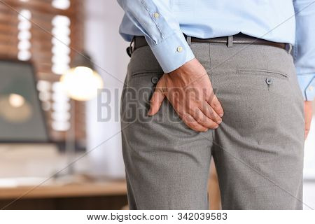 Man Suffering From Hemorrhoid In Office, Closeup