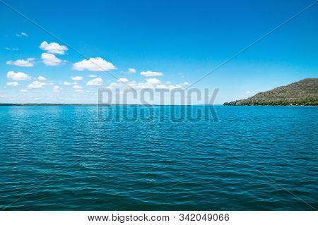 Lake Itza With Cocodrile Shaped Mountain On Sunny Day And Small Clouds, El Remate, Peten, Guatemala