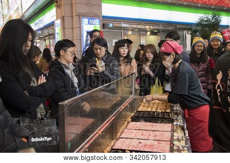 Osaka, Japan- 27 Nov, 2019: Vendor Making Takoyaki On A Takoyaki Pan In Osaka, Japan. Takoyaki Is Fa