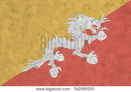 Bhutan Flag Depicted In Bright Paint Colors On Old Relief Plastering Wall. Textured Banner On Rough 