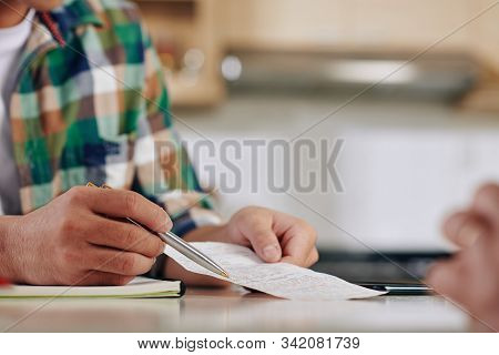 Close-up Image Of Young Man Showing Bill To His Mother And Discussing Ammount Of Money They Need To 
