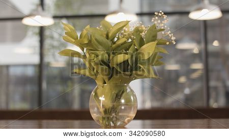 Gentle Lilly Of Valley Flowers In Glass Vase Standing On Wooden Table On Blurred Background With Win