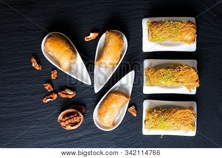Food Concept Oriental Arab Dessert Baklava Walnuts And Rolled Kanafeh On Black Slate Board With Copy