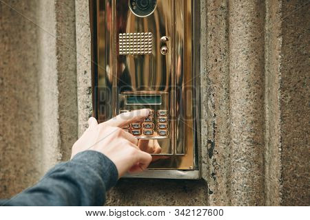 A Male Hand Presses A Doorphone Button For Access Inside.