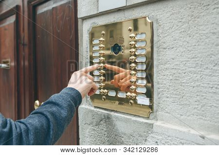 A Male Hand Presses A Doorphone Button For Access Inside.