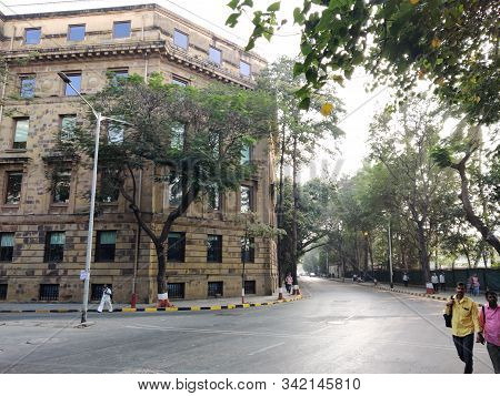 Mumbai, India - April, 2017: Cityscape Of Mumbai With Old Buildings And Empty Street And People Walk