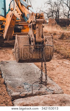 The Worker Grabs Chains Onto The Excavator Bucket To Carry And Install Concrete Slabs On The Road.
