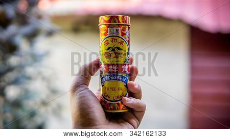 Hand Holding A Yu Yee Oil Cap Limau Metal Bottle Case. It Is A Herbal Medicated Ointment.