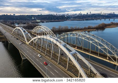 Aerial Top View Of Automobile And Railroad Darnitsky Bridge.