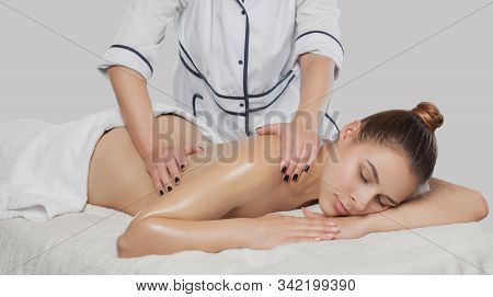 Masseur Makes A Relaxing Massage On The Neck, Shoulders, Back And Collarbones Of A Young Beautiful W