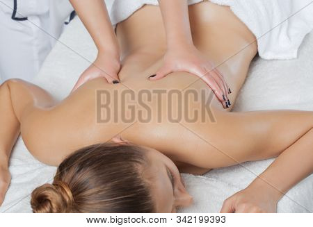 Masseur Makes A Relaxing Massage On The Neck, Shoulders, Back And Collarbones Of A Young Beautiful W