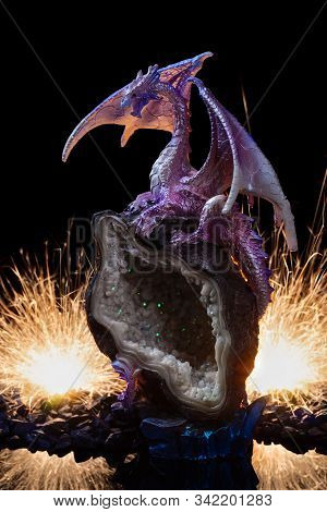 A Ceramic Statuette Of White Pink Dragon On White-green Stone With Fire And Sparks On Background