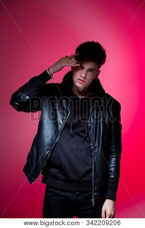 Cute Brutal Man In Black Leather Jacket Model Style. Portrait Of A Handsome Guy On Pink Studio Backg