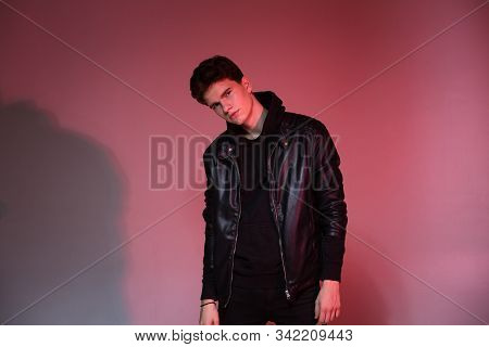 Cute Brutal Man In Black Leather Jacket Model Style. Portrait Of A Handsome Guy On Pink Studio Backg