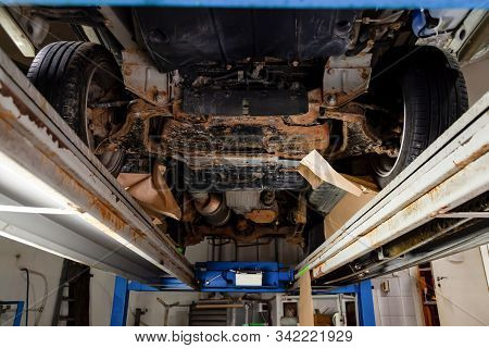 The Bottom Of The Car Lifted On A Lift Covered With Brown And Orange Rust During Anti-corrosion Trea