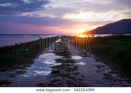 Path Towards Orange Sunset On Dramatic Purple Blue Sky Along Lake Itza, El Remate, Peten, Guatemala