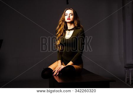 Beautiful Dancer. Girl Model. The Girl Sits In A Hat And Sits On A Table. Girl In A Beautiful Underw