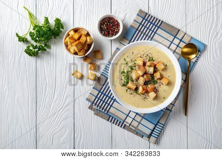 A Portion Of Asiago Roasted Garlic Cauliflower Soup  In A White Bowl Topped With Croutons, Horizonta