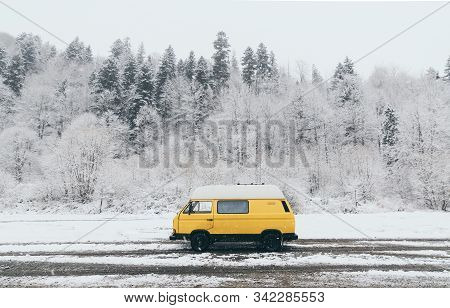 Carpathians, Ukraine - December 2019: Yellow Camper Van With Winter Forest On Background