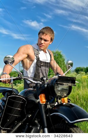 Przystojny mężczyzna w Boilersuit, stojący w pobliżu motocykl.