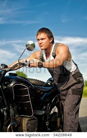 Przystojny mężczyzna w Boilersuit toczenia motocykl.