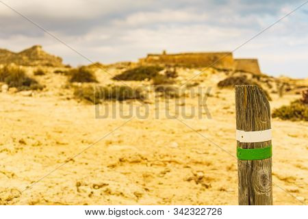 Green White Trail Hiking Sign On Mediterranean Coast. Castle San Ramon In The Background. Beach Of E