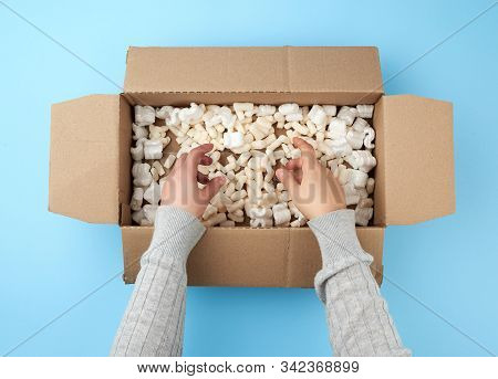 Two Female Hands Hold An Empty Open Box Of Brown Cardboard, At The Bottom There Is A White Foam For 