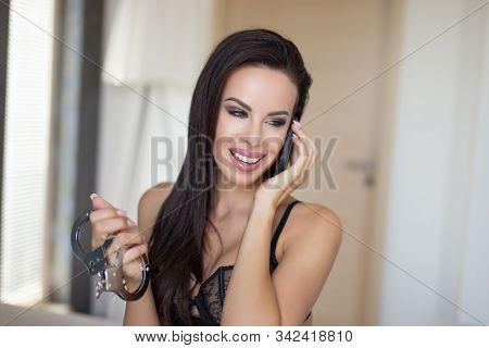 Sensual Brunette Woman Calling And Holding Handcuffs Portrait, Bdsm