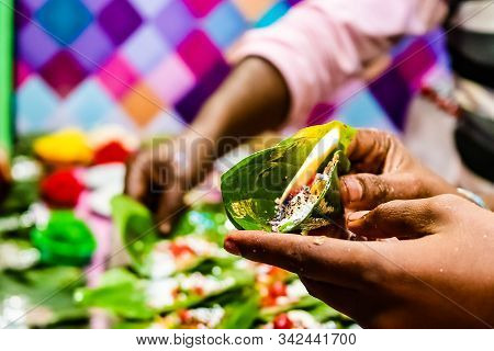 Hand Of A Seller Holding Fire Paan, Betel Leaf On Flame.