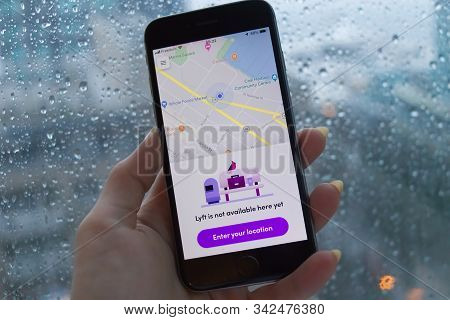 Vancouver, Canada - December 31, 2019: A Woman Is Holding A Phone With Lyft App During The Heavy Rai