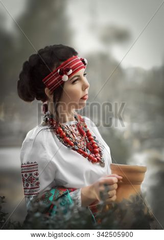 A Half-face Portrait Of A Pretty Young Female Dressed In A Ukrainian Folk Costume Holding A Clay Jug
