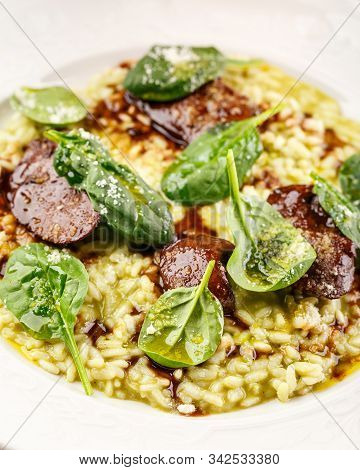 Risotto With Spinach And Chicken Liver Garnished With Spinach Leaves And Parmesan Cheese. Restaurant