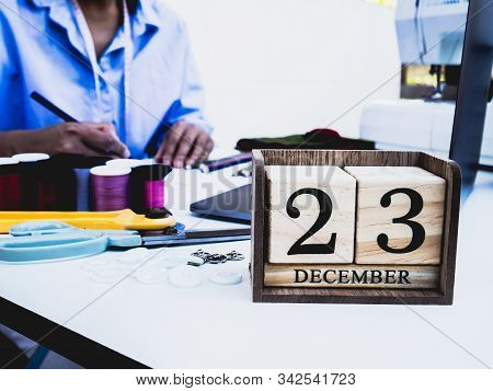 23 Decembar Wooden Calender With Designer And Sewing Equipment, Laptop, Smartphone On White Backgrou