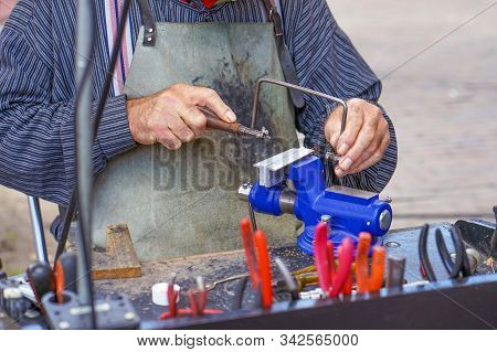Elderly Male Working On Machine Tool For Metal. Old Man At The Workplace With Tools. Retirement Hobb