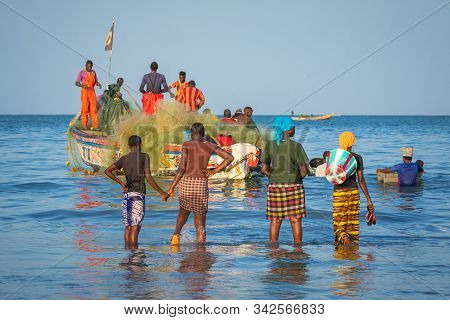 Tanji, The Gambia - November 21, 2019: Scene With Men And Women Carrying Fish From The Boats To The