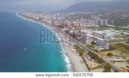 Aerial View Of Mountains Covered By Green Forest With A Coastal City By The Sea On A Sunny Day. Art.