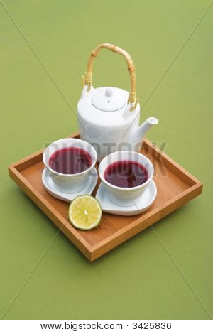 与两个杯子、 茶壶和柠檬木制托盘上的品尝的茶