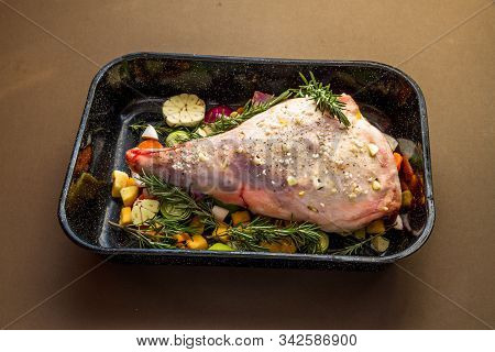 Raw Leg Of Lamb In Roasting Tray Dressed With Vegetables.