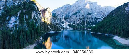Braies Lake in Dolomites mountains forest trail in background, Sudtirol, Italy. Lake Braies is also known as Lago di Braies. The lake is surrounded by forest which are famous for scenic hiking trails.