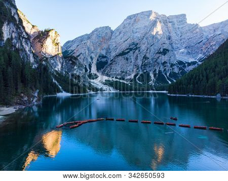 Braies Lake in Dolomites mountains forest trail in background, Sudtirol, Italy. Lake Braies is also known as Lago di Braies. The lake is surrounded by forest which are famous for scenic hiking trails.