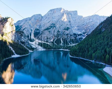 Braies Lake in Dolomites mountains forest trail in background, Sudtirol, Italy. Lake Braies is also known as Lago di Braies. The lake is surrounded by forest which are famous for scenic hiking trails.