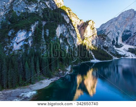 Braies Lake in Dolomites mountains forest trail in background, Sudtirol, Italy. Lake Braies is also known as Lago di Braies. The lake is surrounded by forest which are famous for scenic hiking trails.