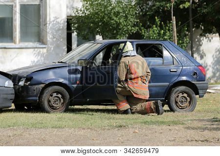 Firefighters Participate In A Training Where They Extinguish Fire From A Car Crashed Into Another Ve